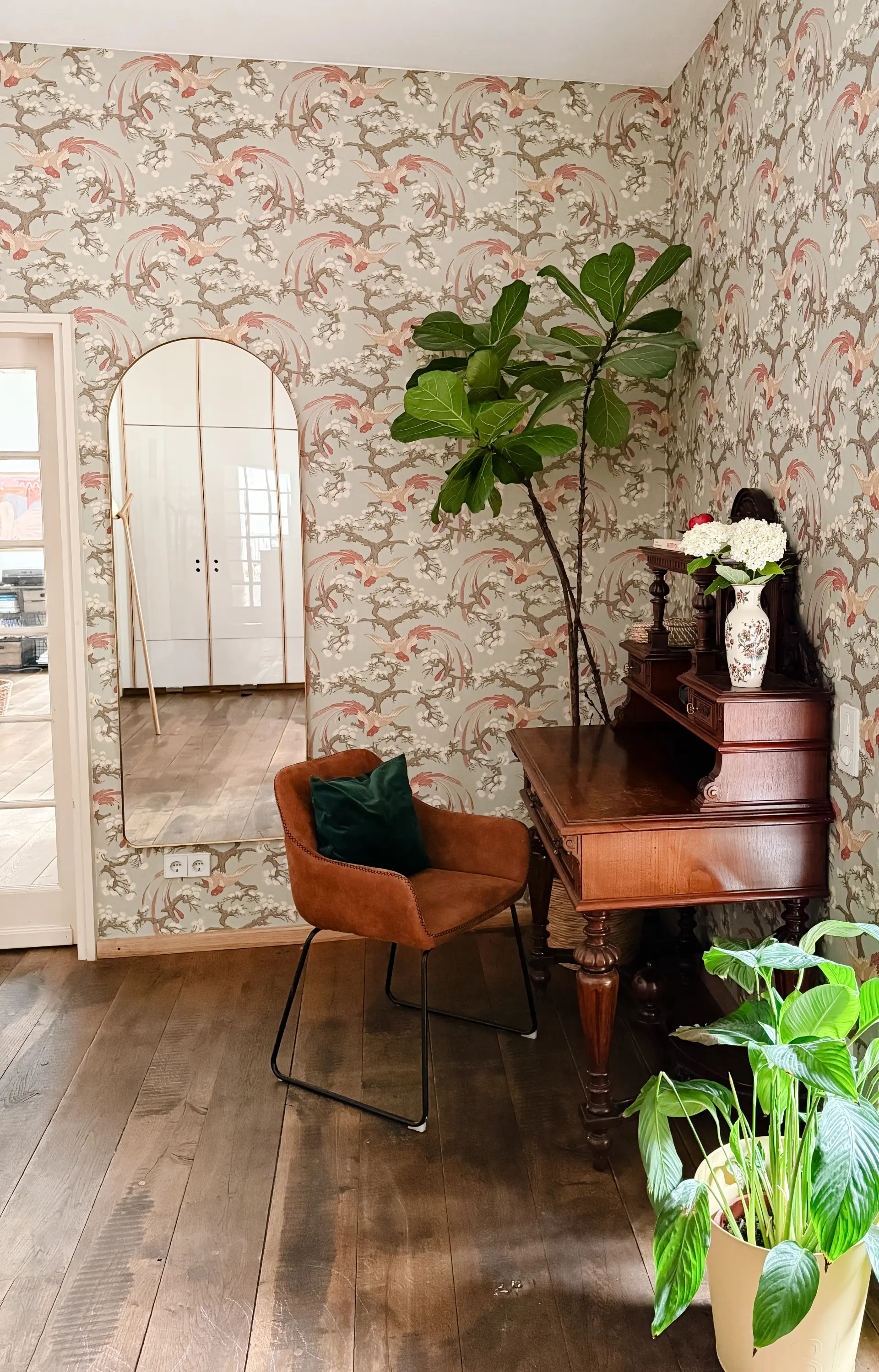 Wohnraum im Modern-Heritage-Stil mit floraler Chinoiserie-Tapete, Cognac-farbenem Samtsessel, antikem Sekretär und bodentiefem Bogenspiegel – Projekt Art of Home von Studio Olivia Interior