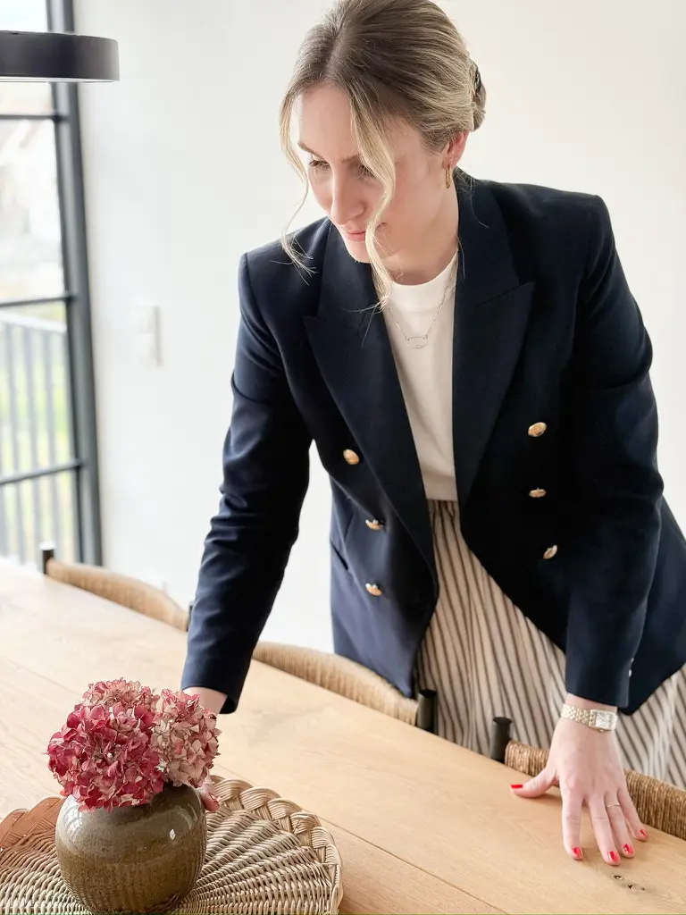 Nora-Aileen Koch rückt eine Vase mit getrockneten Hortensien auf einem Eichen-Esstisch zurecht – Studio Olivia Interior