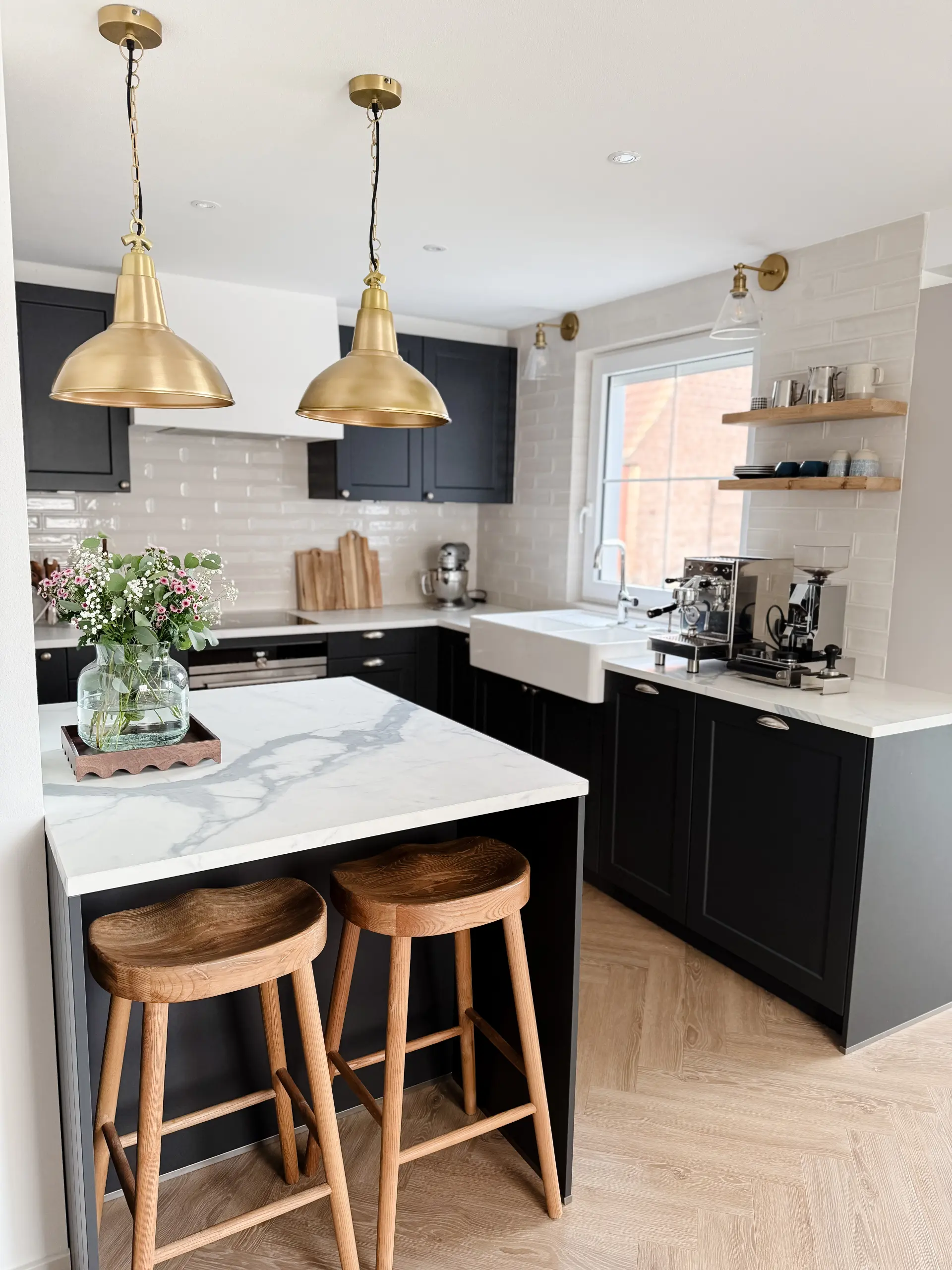 Von Studio Olivia Interior gestaltete Küche mit dunklen Fronten, Messing-Pendelleuchten und Marmor-Kochinsel